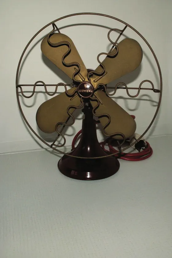 An early electric desk fan with brass blades in a wire cage.